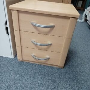 Light coloured three drawer bedside table